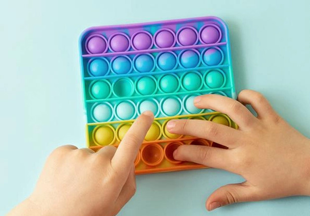 Hands playing with a push pop given as promotional fidget