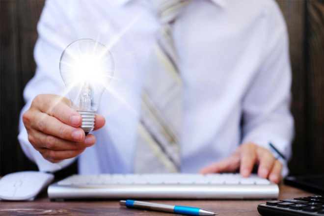 Man at his desk holding a light bulb